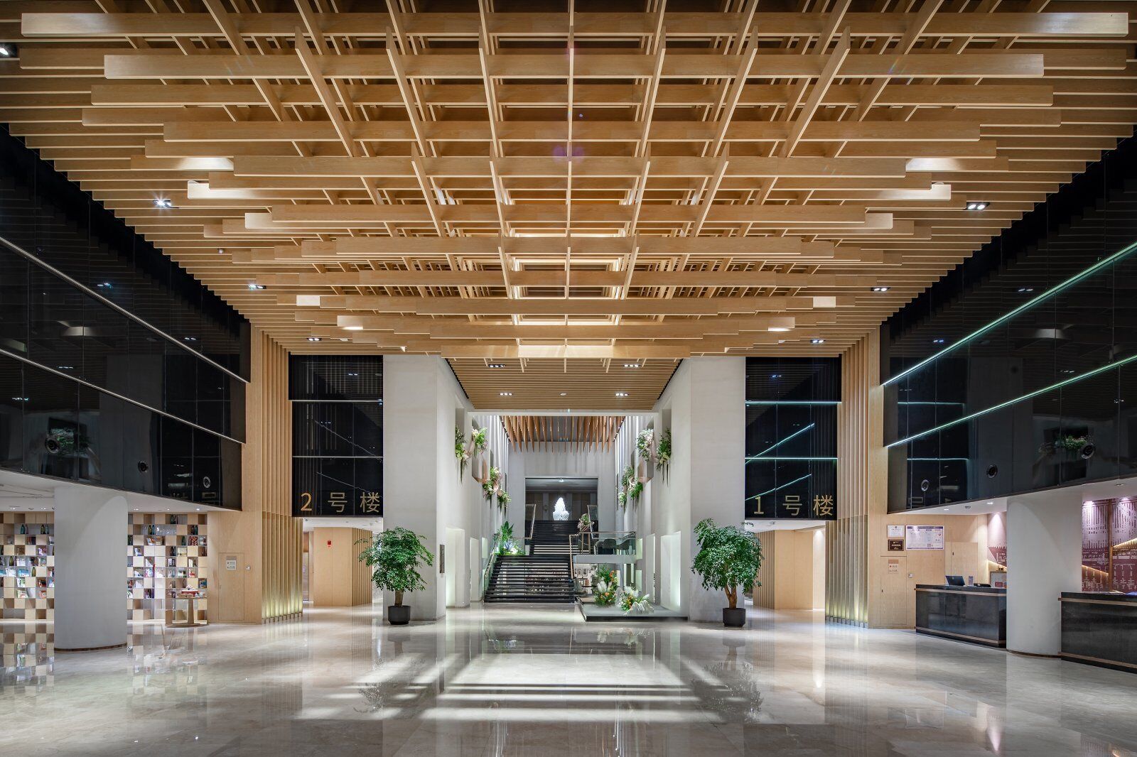 Un vestíbulo moderno con techo de madera, una escalera central y un mostrador de recepción.
