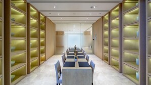 A conference room with a long table and chairs, surrounded by wooden shelving units with illuminated sections. - Garrya Xi'an Lintong (Xi'an)