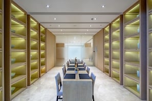 A conference room with a long table and chairs, surrounded by wooden shelving units with illuminated sections. - Garrya Xi'an Lintong (Xi'an)
