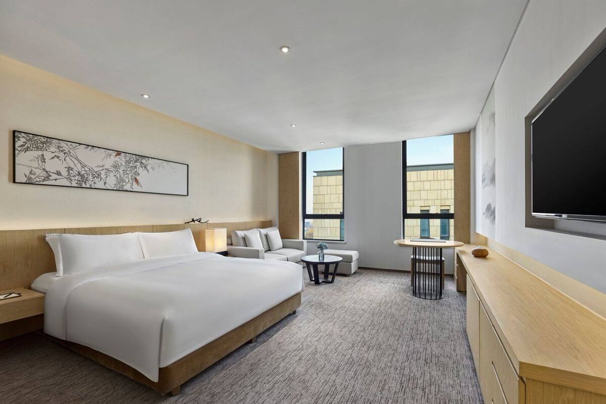Une chambre d’hôtel moderne équipée d’un grand lit, d’un bureau, d’une chaise et d’un téléviseur.