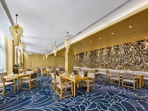 A hotel dining area with tables and chairs, a patterned carpet, and a wall of framed photos. - Garrya Xian Lintong (Xi'an)