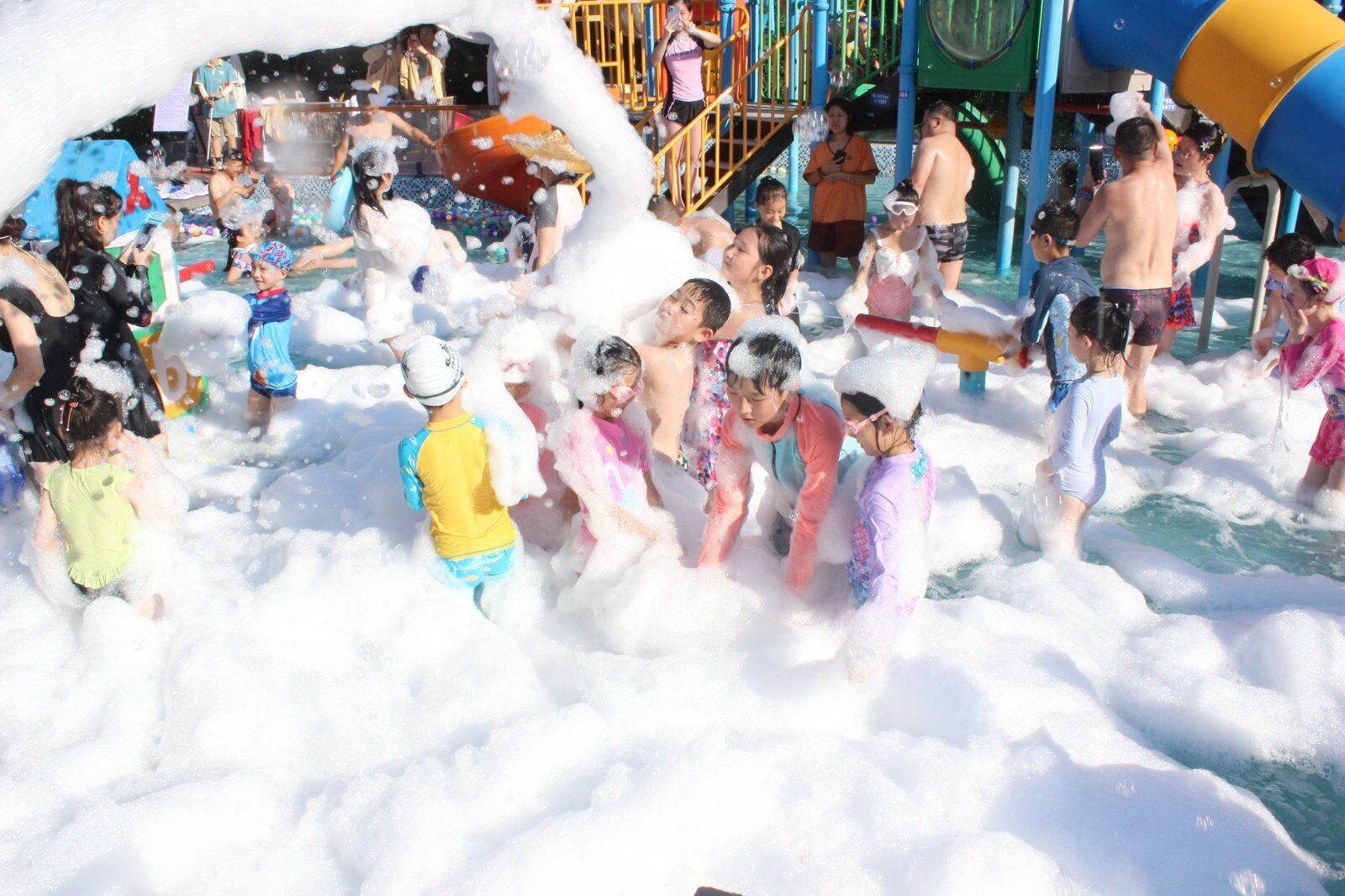 A water play area with children and adults engaged in water activities.