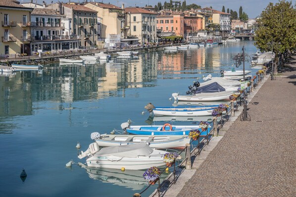 A canal lined with boats, buildings, and a cobblestone path.