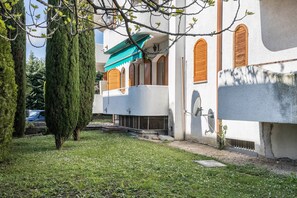 Un bâtiment à l’extérieur blanc, avec des volets en bois et un auvent vert.