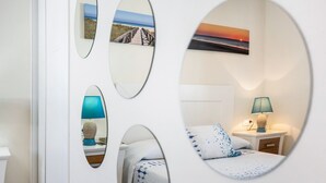 Ein Schlafzimmer mit Bett, Nachttisch, Lampe und wandmontierten Spiegeln, die verschiedene Szenen widerspiegeln.
