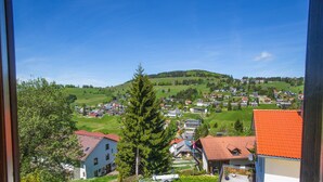 Une vue d’un village avec des maisons et un grand arbre au premier plan.