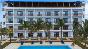 A multi-story hotel with balconies, a swimming pool, and palm trees.