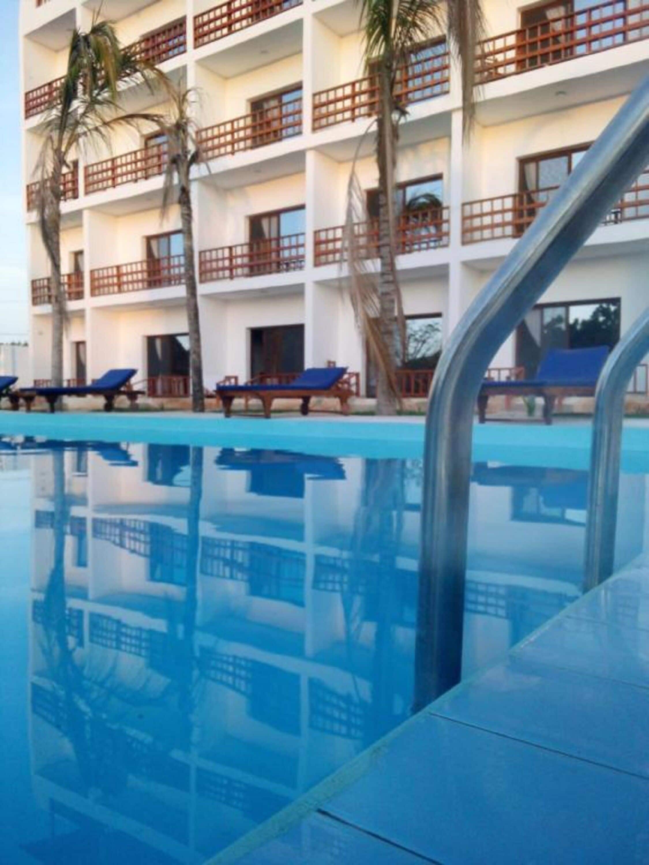 Un hotel con piscina, varios balcones y sillones de descanso.