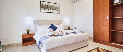 Un dormitorio con una cama grande, mesitas de noche, un armario y un cuadro enmarcado en la pared.