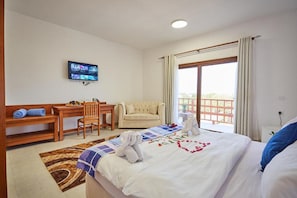 A hotel room with a bed, a desk, a chair, a television, and a balcony with curtains.