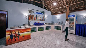 A reception area with a marble floor, a ceiling fan, a painting of a family, and a refrigerator labeled "Al-Rabie".