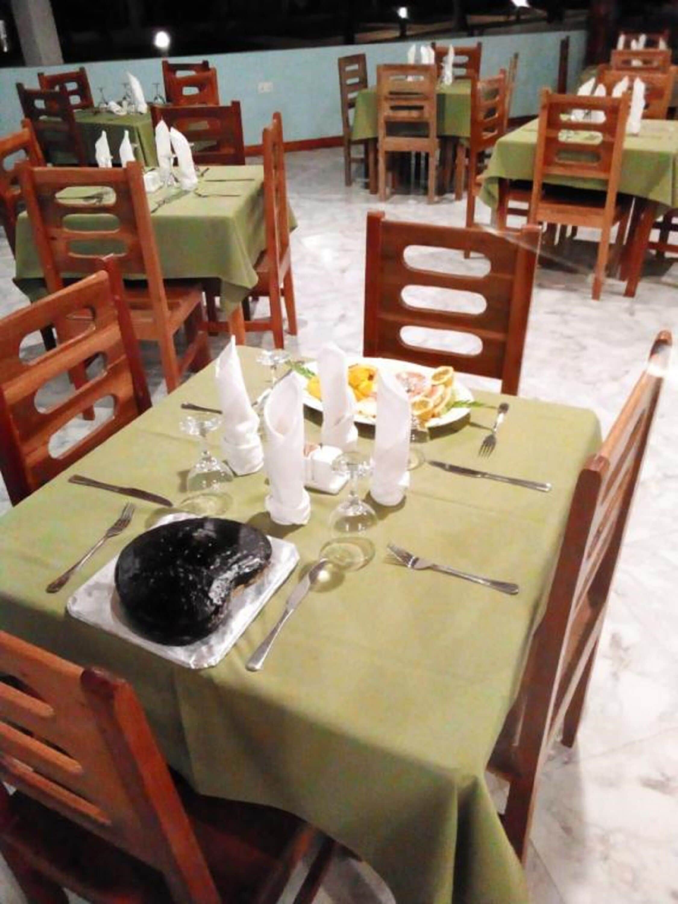 A restaurant with tables set for dining, chairs, and a dessert plate on one table.