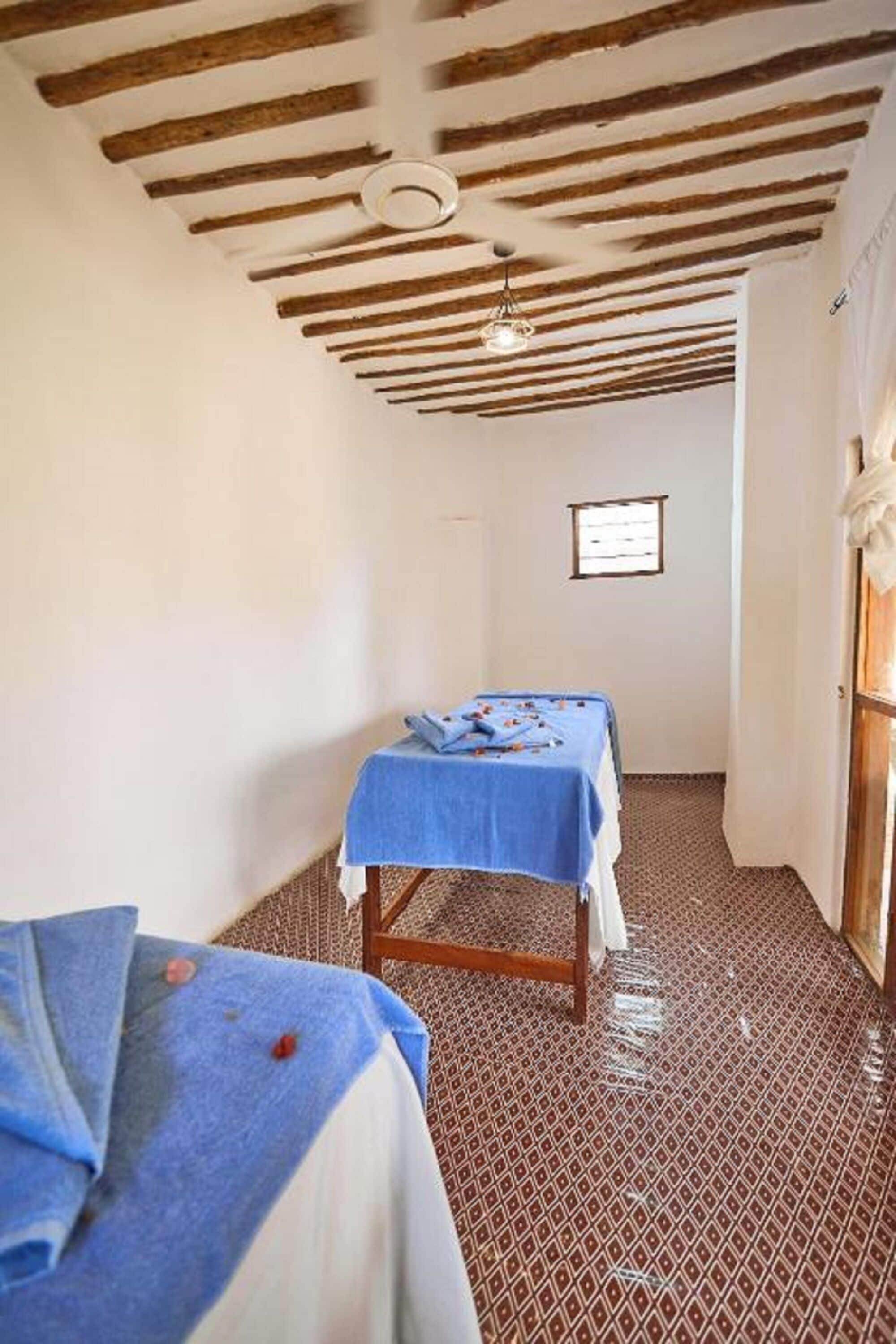 Habitació amb dos llits, un sostre de fusta i un paviment amb dibuixos.