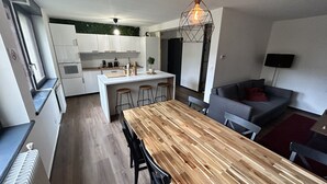 A modern kitchen with white cabinets, a wooden dining table, and bar stools. - High comfort accommodation | Le Puy en Velay (Le Puy-en-Velay)