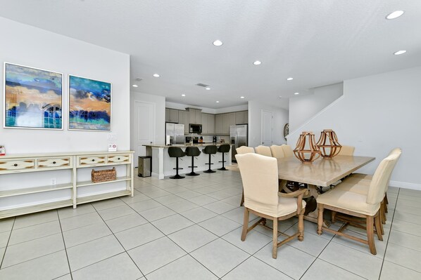 A modern kitchen with white cabinets, a central island, and bar stools.