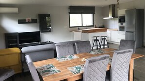 A modern living space with a dining area, kitchen, and entertainment setup. - 4-bedroom family house with sauna, garden and terrace - near south beach (Lacanau)