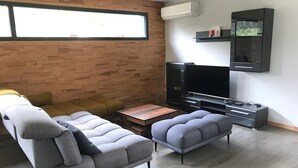 A modern living room with a sectional sofa, a coffee table, a flat-screen TV, and a built-in entertainment unit. - 4-bedroom family house with sauna, garden and terrace - near south beach (Lacanau)