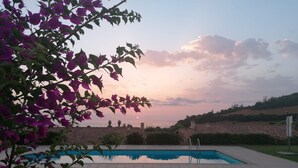 A swimming pool with a view of the sunset, surrounded by greenery and buildings. - Holiday Home "Casa del Sole" with Sea View, Pool, Garden & Wi-Fi (TERTENIA)