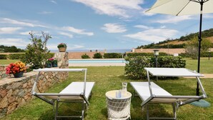 A poolside area with lounge chairs, a table, and an umbrella. - Holiday Home "Casa del Sole" with Sea View, Pool, Garden & Wi-Fi (TERTENIA)