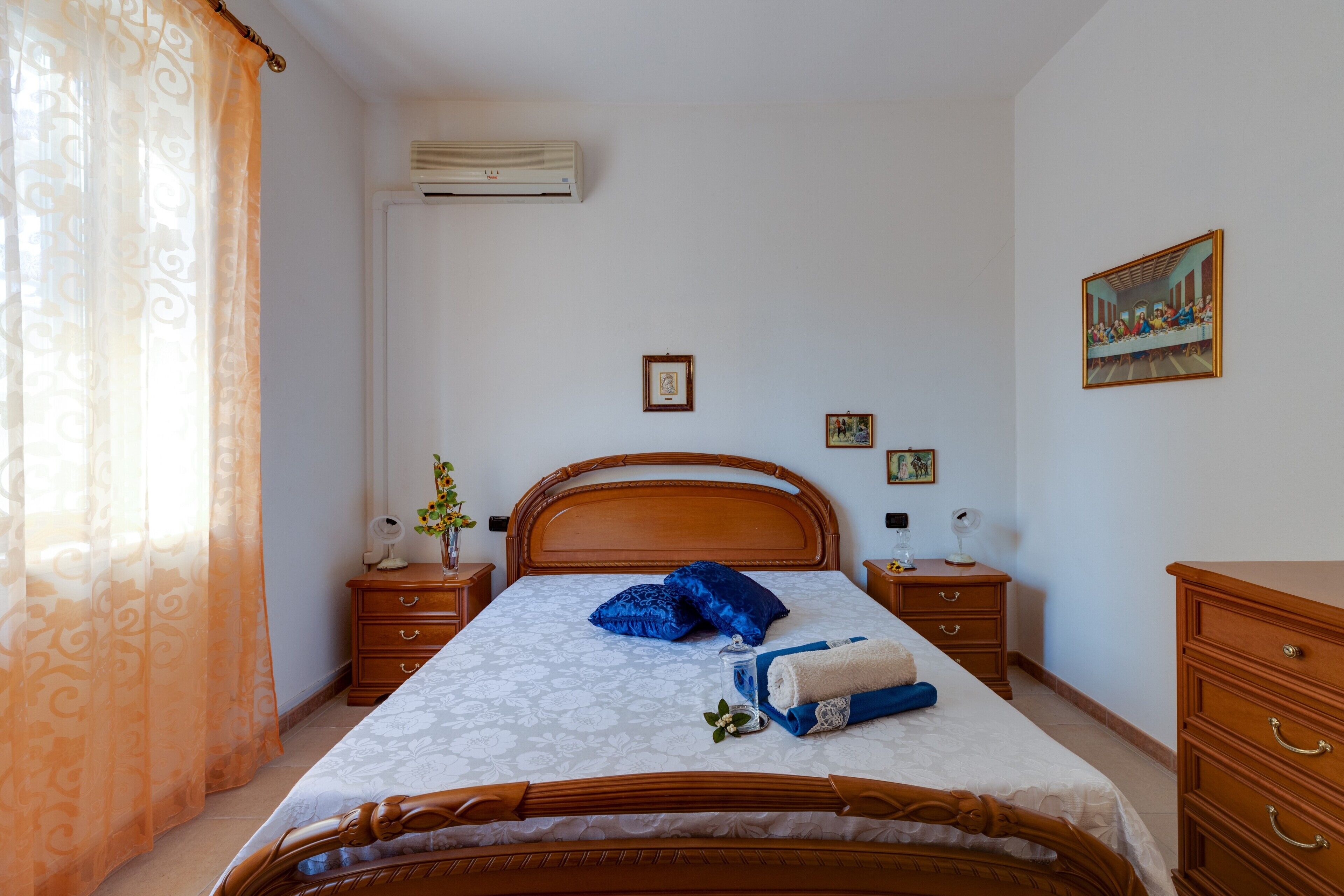 A bedroom with a wooden bed, a nightstand, a dresser, and a painting on the wall.