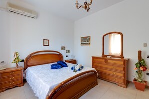 Une chambre à coucher avec un lit en bois, une commode, un miroir et une plante en pot.