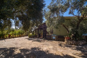 A courtyard with a stone floor, a wooden pergola, and potted plants. - Holiday Home "Lilliu" with Mountain View, Garden & Air Conditioning (VILLACIDRO)