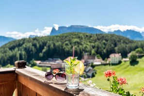 A wooden deck with a glass of water, sunglasses, and a mountain view. - Apartment 'Sallrain Hof 2' with Mountain View & Balcony (Klobenstein)