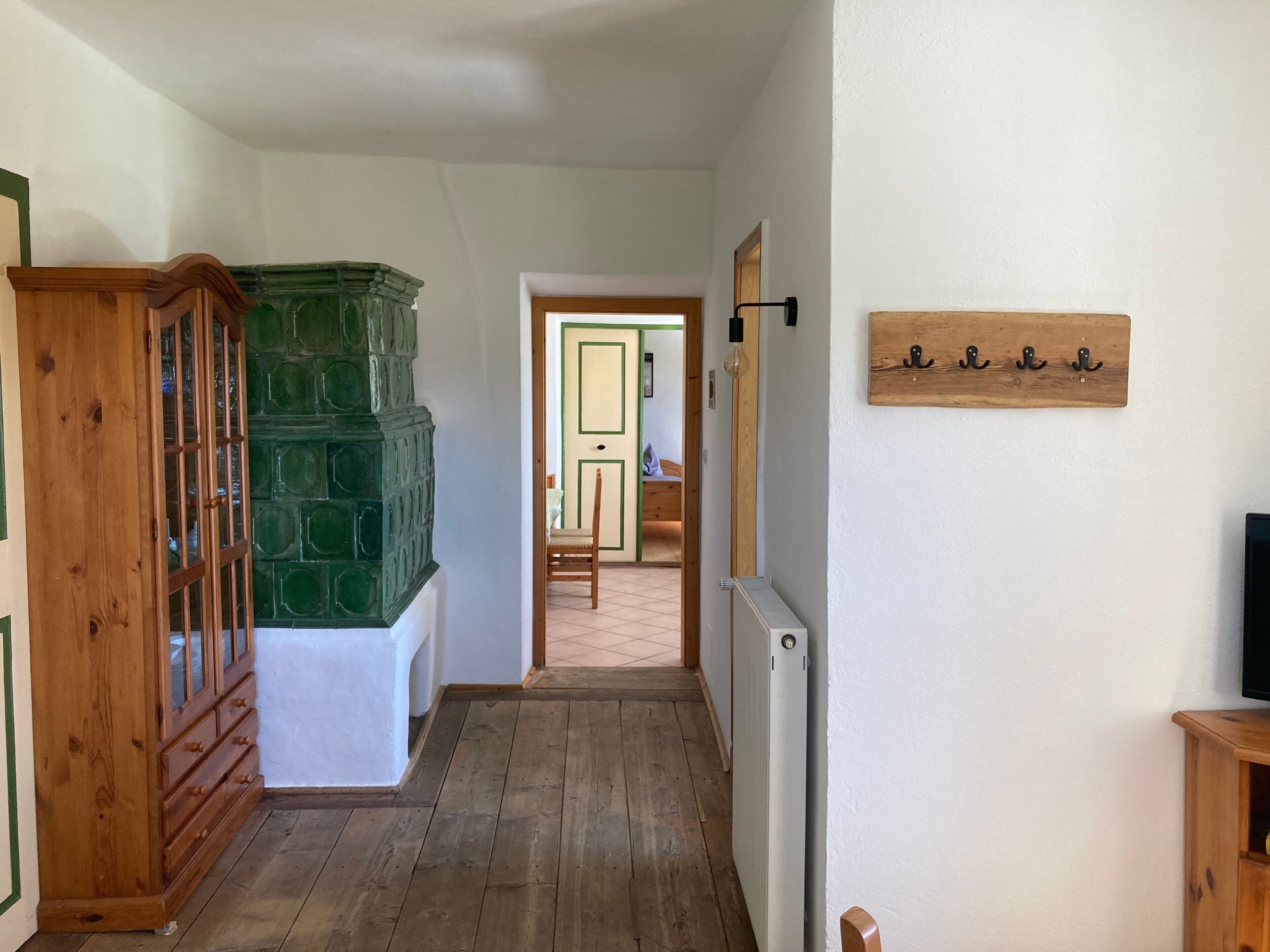 A hallway with a wooden cabinet, a radiator, and a wall-mounted coat rack.