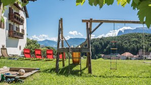 Ein Weinberg mit einer Holzhütte, roten Stühlen und Blick auf die Berge.