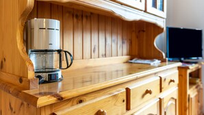 Eine Holzausziehtisch mit einer Kaffeemaschine, einer Glaskaraffe und einem Fernseher.