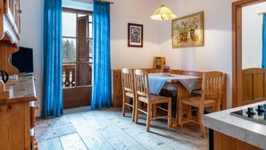 Ein Holzespeisetisch mit Stühlen, einem Fernseher und einem Fenster mit blauen Vorhängen.