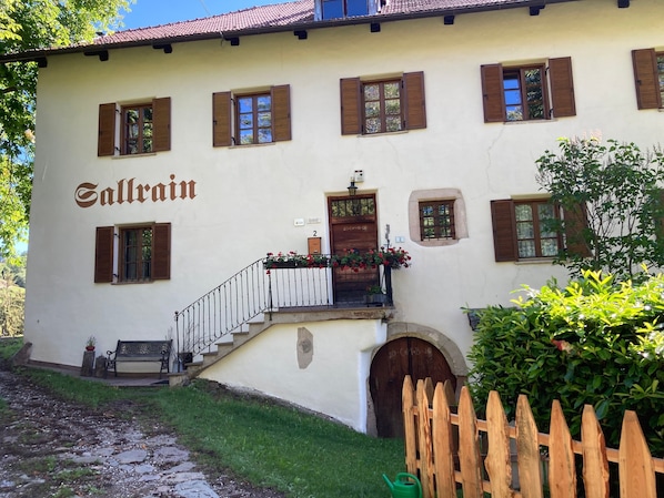 A building with the name 'Sallrain' on the facade, a wooden fence, and a bench outside.