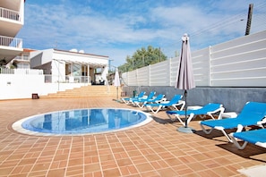 A swimming pool with blue lounge chairs and a white building with a balcony. - Apartment 'Costa Cabanas 1' near the Beach with Shared Pool & Wi-Fi (Cabanas de Tavira)