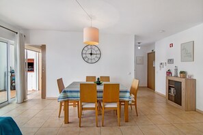 Un comedor con una mesa, sillas, un reloj y una lámpara colgante.