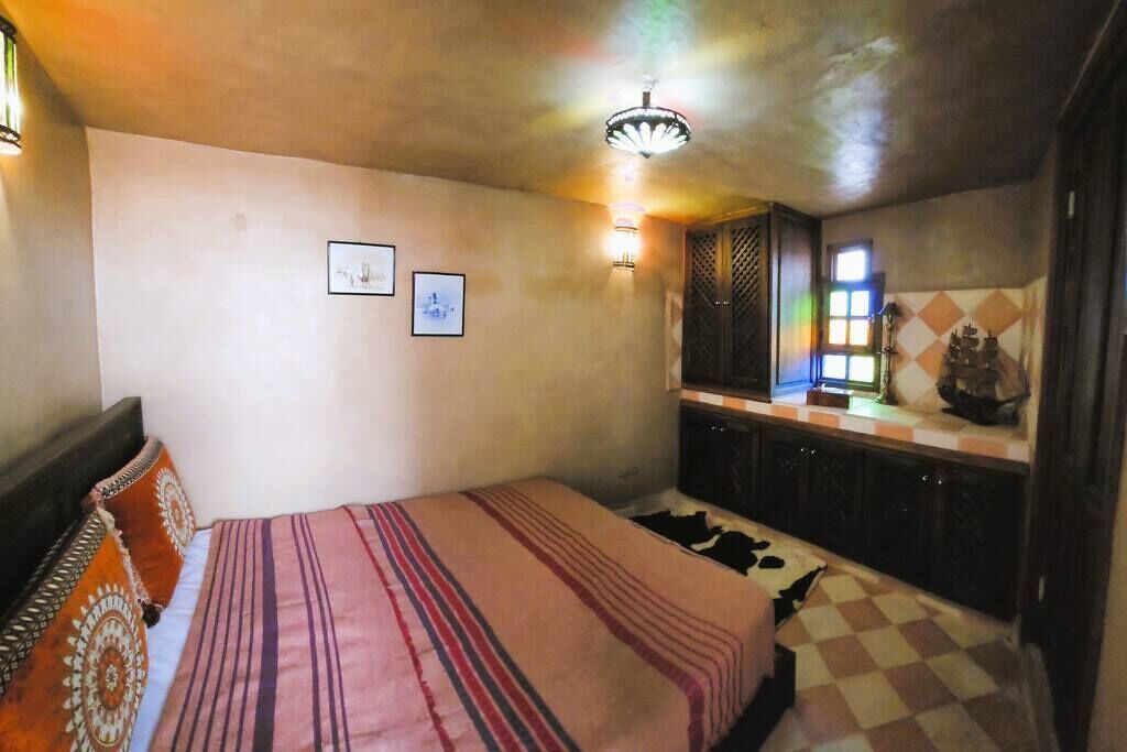 A bedroom with a bed, a nightstand, a dresser, and a window with a view.