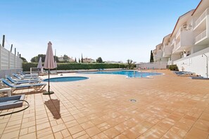 A pool area with lounge chairs, umbrellas, and a tiled floor. - Costa Cabanas 56 Apartment near the Beach with Shared Pool & Wi-Fi (Tavira)