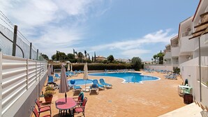 Un espace piscine aménagé sur le toit, avec des chaises longues, une table et un petit jardin.