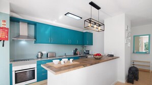 Une cuisine moderne avec des armoires de couleur turquoise, un plan de travail en bois et un four encastré.