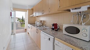 Une cuisine moderne avec des meubles en bois, un lave-vaisselle Bosch, un four à micro-ondes et une machine à café.