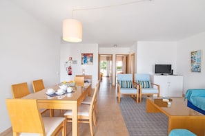 A modern hotel room with a dining area, a living room, and a TV.