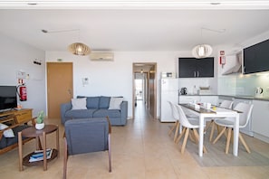 Un appartement moderne comprenant un salon, un coin repas, une kitchenette et un couloir menant à une autre pièce.