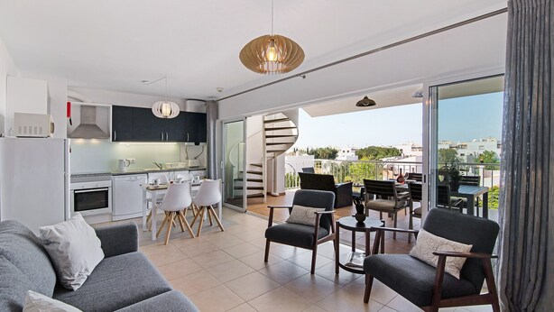 A modern living room with a sofa, chairs, a dining area, and a kitchen.