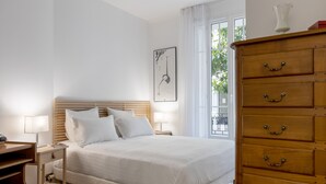 A neatly arranged bedroom with a wooden bed, bedside tables, and a dresser. - Almond Blossom, by Veeve (Paris)