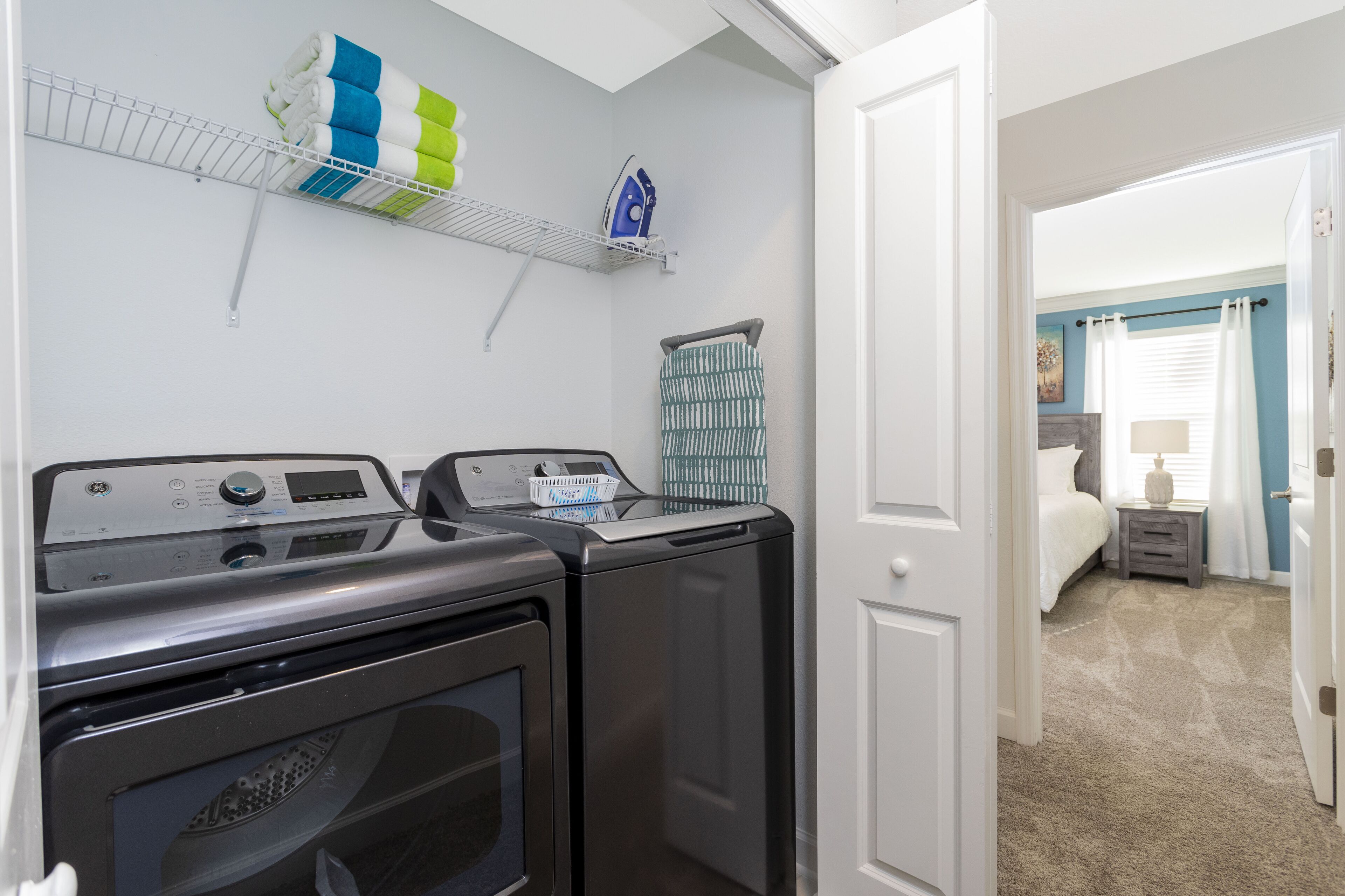 A laundry area with two washing machines, a drying rack, and a basket.