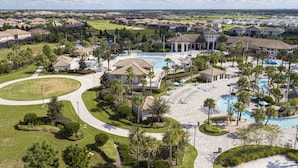 Un complejo turístico con piscina central, varias zonas de descanso y un campo de golf al fondo.