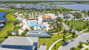 An aerial view of a resort with multiple swimming pools, a central gazebo, and a large body of water. - Gorgeous 3Bd 8 Guests @Storey Lake Resort Close to Disney 101 3191 (Kissimmee)