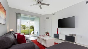 A modern living room with a grey sofa, red pillows, a white coffee table, and a flat-screen TV mounted on the wall. - Gorgeous 3Bd 8 Guests @Storey Lake Resort Close to Disney 101 3191 (Kissimmee)