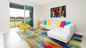 A modern living room with a white sofa, colorful cushions, a glass coffee table, and a vibrant rug. - Family Friendly 2 Bd Close to Disney @ Storey Lake 105 3161 (Kissimmee)