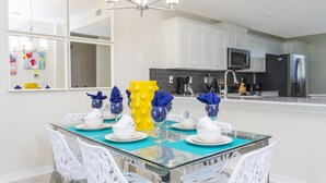 A modern kitchen with white cabinets, a black refrigerator, and a glass dining table with white chairs. - Family Friendly 2 Bd Close to Disney @ Storey Lake 105 3161 (Kissimmee)