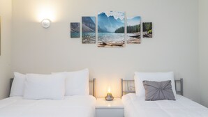 A hotel room with two beds, a nightstand with a lamp, and a wall-mounted artwork of a mountain landscape. - Stunning 2Bd Apto Close to Disney @ Storey Lake 105 3171 (Kissimmee)
